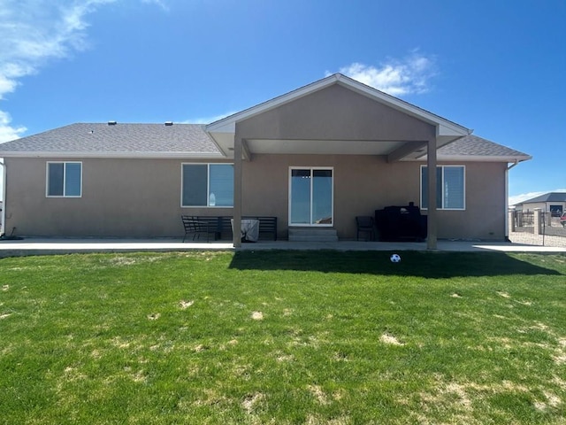 rear view of property featuring a lawn, a patio area, and stucco siding
