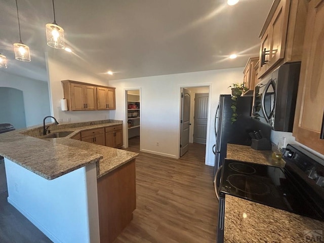 kitchen with light stone countertops, a sink, dark wood finished floors, stainless steel appliances, and a peninsula