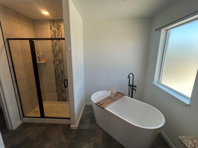 bathroom with a soaking tub, baseboards, a wealth of natural light, and a stall shower