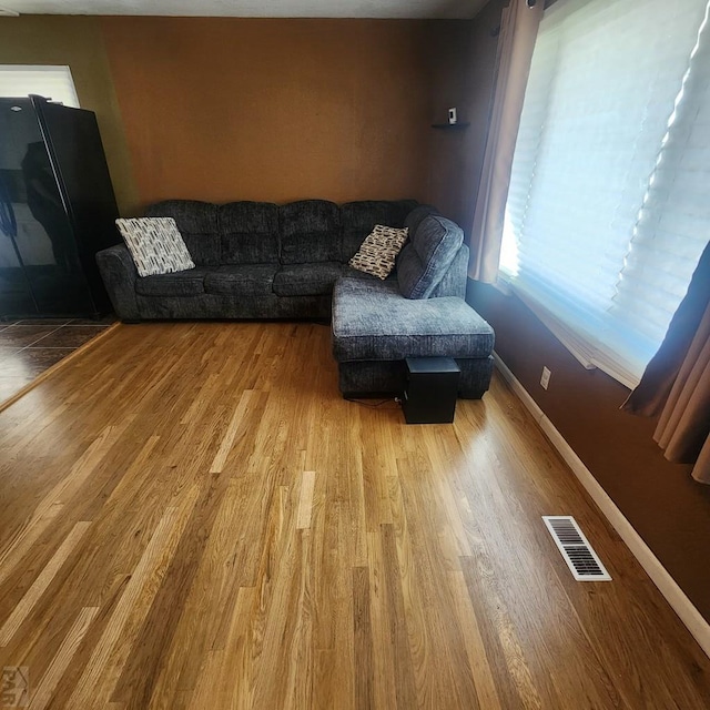 living area featuring baseboards, visible vents, and wood finished floors