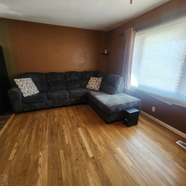 living room with visible vents, baseboards, and wood finished floors