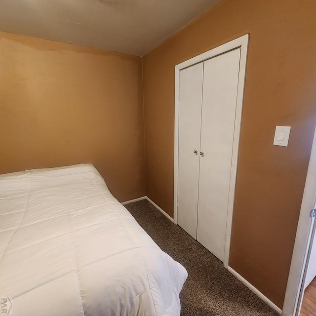 carpeted bedroom with a closet and baseboards