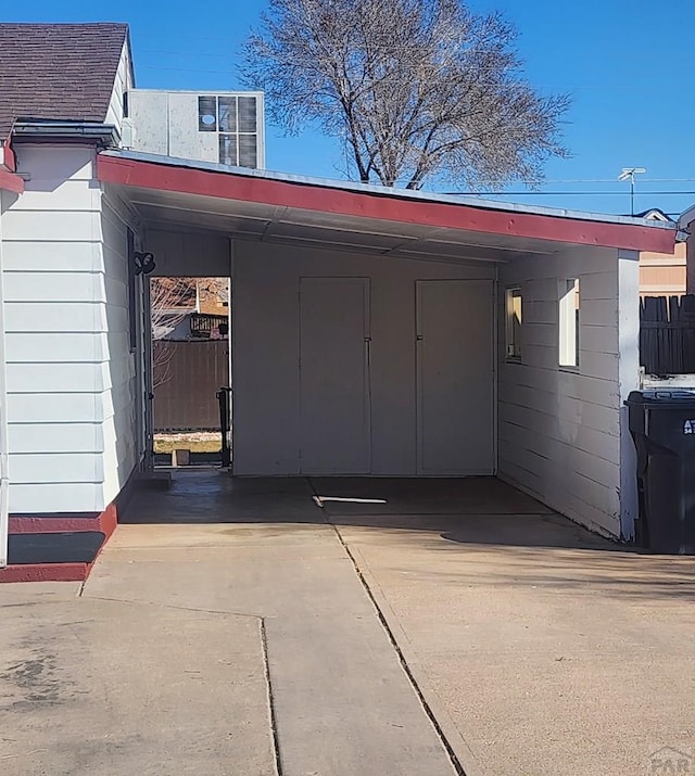 exterior space featuring concrete driveway, an attached carport, and fence