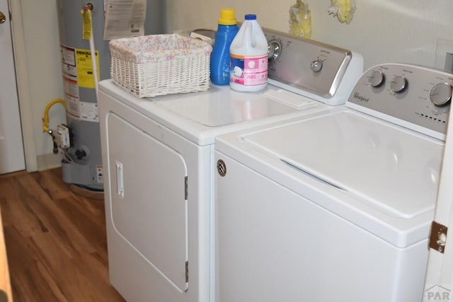 clothes washing area featuring wood finished floors, laundry area, water heater, and separate washer and dryer