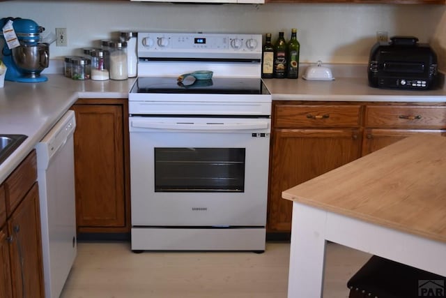 kitchen with white appliances, brown cabinets, and light wood finished floors