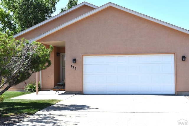 view of front of home featuring a garage, concrete driveway, and stucco siding