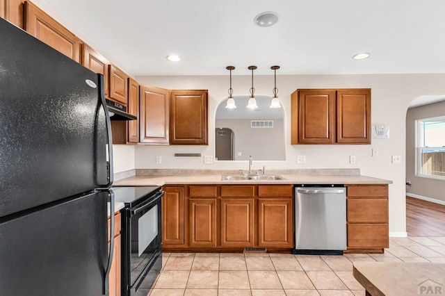 kitchen featuring visible vents, arched walkways, light countertops, black appliances, and a sink