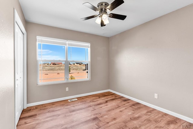 unfurnished room featuring light wood finished floors, visible vents, and baseboards