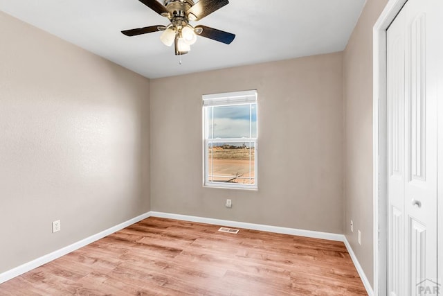 empty room with light wood-style floors, baseboards, visible vents, and a ceiling fan