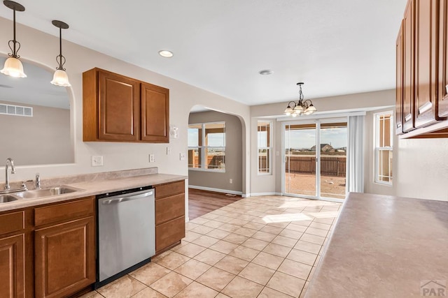 kitchen featuring a sink, visible vents, hanging light fixtures, dishwasher, and brown cabinetry