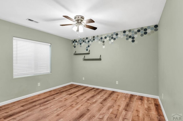 unfurnished room with a ceiling fan, visible vents, light wood-style floors, and baseboards