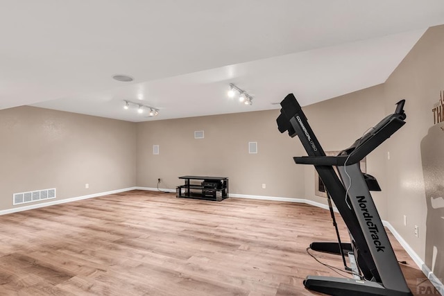 exercise area featuring light wood finished floors, baseboards, visible vents, and track lighting