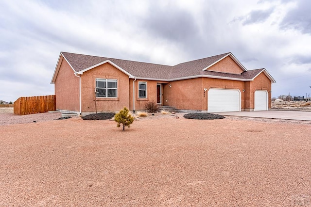 ranch-style house with an attached garage, driveway, fence, and stucco siding