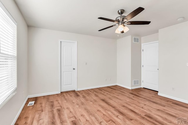 unfurnished room featuring light wood-style flooring, visible vents, and baseboards