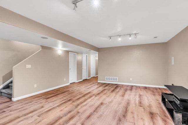 interior space featuring light wood-style floors, baseboards, visible vents, and track lighting