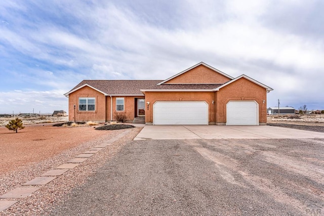 ranch-style house featuring a garage, driveway, and stucco siding