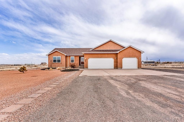 ranch-style house with driveway, an attached garage, and stucco siding