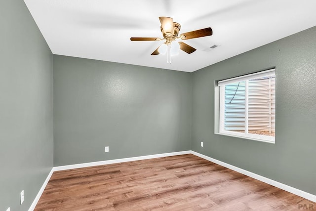 spare room featuring a ceiling fan, baseboards, visible vents, and wood finished floors