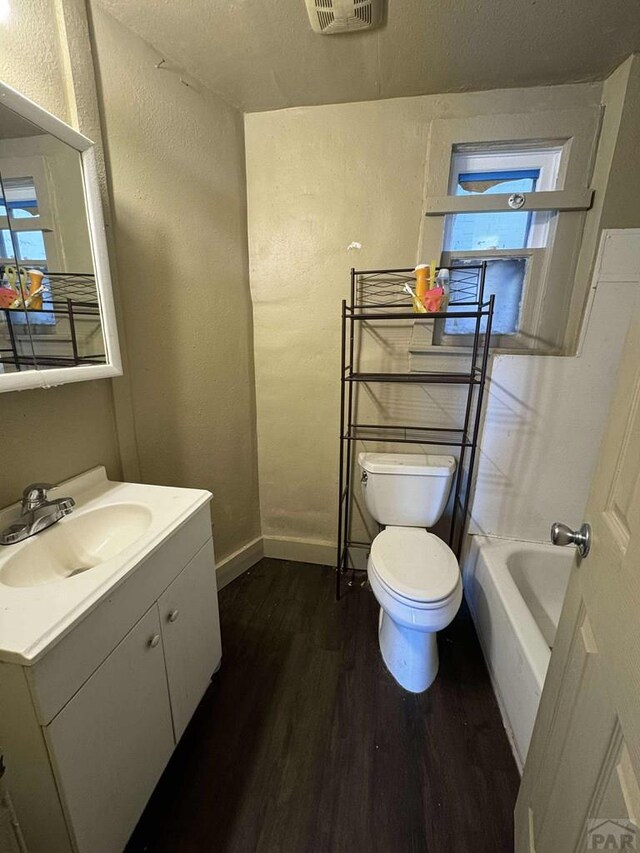 full bath with visible vents, toilet, vanity, wood finished floors, and baseboards