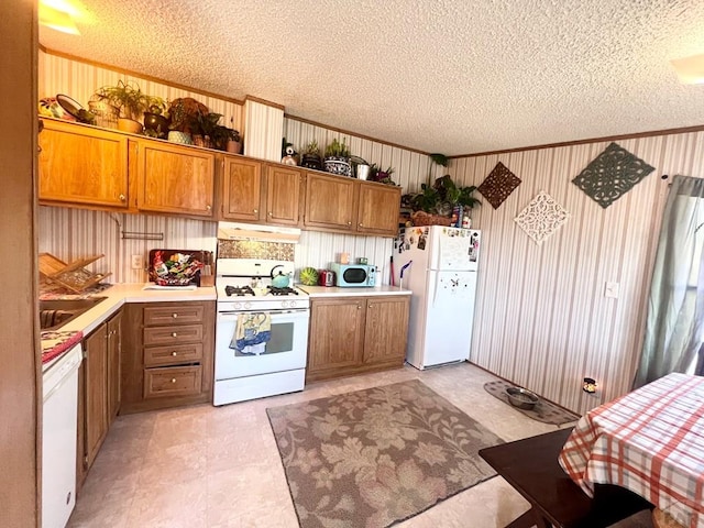 kitchen featuring brown cabinets, white appliances, light countertops, and under cabinet range hood