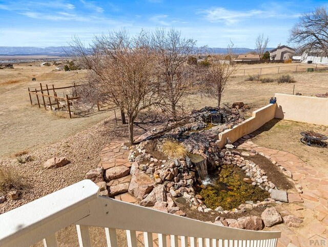 view of yard with an outdoor fire pit, fence, and a balcony