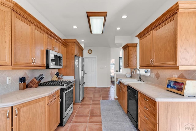 kitchen featuring light tile patterned floors, tile countertops, stainless steel appliances, a sink, and backsplash