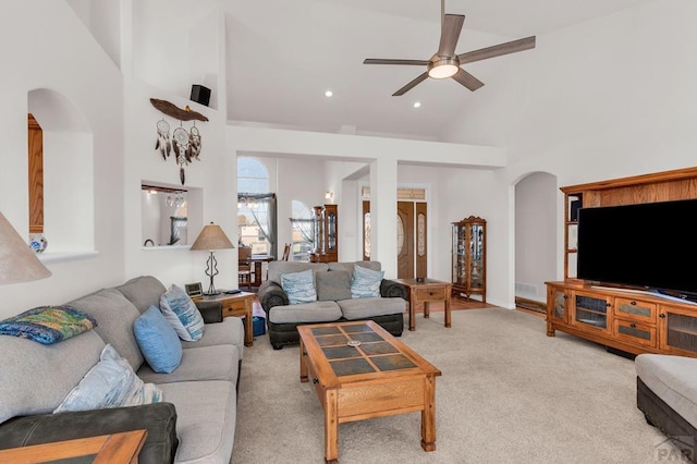 living area with light carpet, high vaulted ceiling, arched walkways, and a ceiling fan