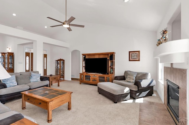 living room featuring arched walkways, recessed lighting, ceiling fan, high vaulted ceiling, and a tile fireplace