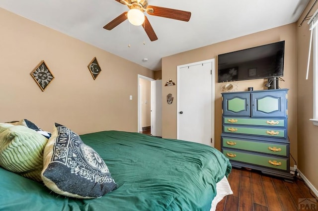 bedroom with a ceiling fan, baseboards, and dark wood-type flooring