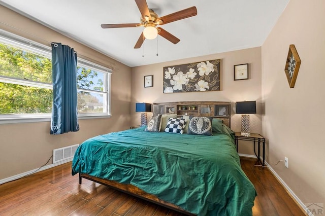 bedroom with visible vents, a ceiling fan, baseboards, and wood finished floors