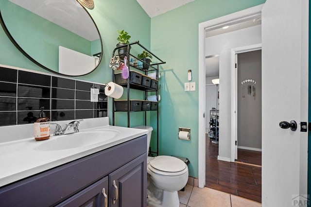 half bathroom featuring vanity, baseboards, tile patterned floors, and toilet