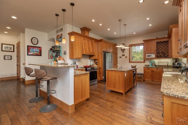 kitchen featuring appliances with stainless steel finishes, wood-type flooring, a sink, and visible vents