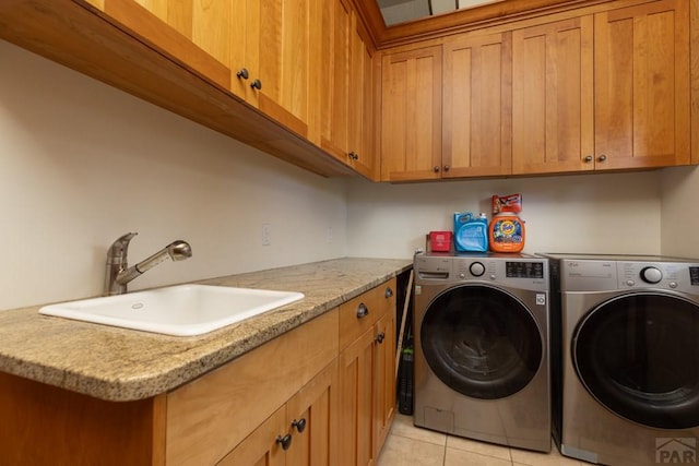 laundry room with cabinet space, light tile patterned floors, washer and clothes dryer, and a sink