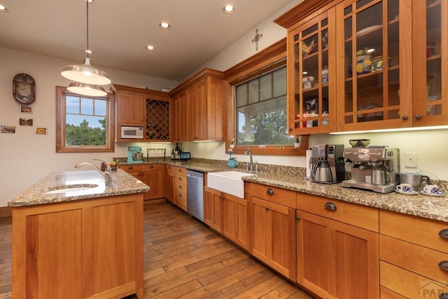 kitchen with light stone counters, light wood finished floors, white microwave, a sink, and dishwasher