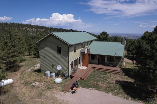 view of front facade with a chimney, metal roof, a deck, and central air condition unit