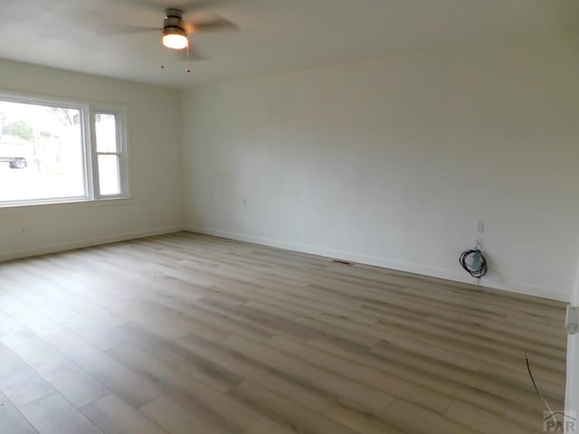 unfurnished room with light wood-style flooring, visible vents, baseboards, and a ceiling fan