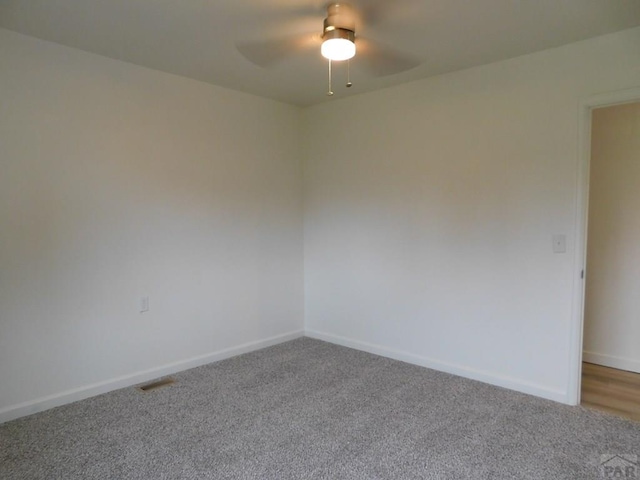 carpeted empty room with a ceiling fan, visible vents, and baseboards