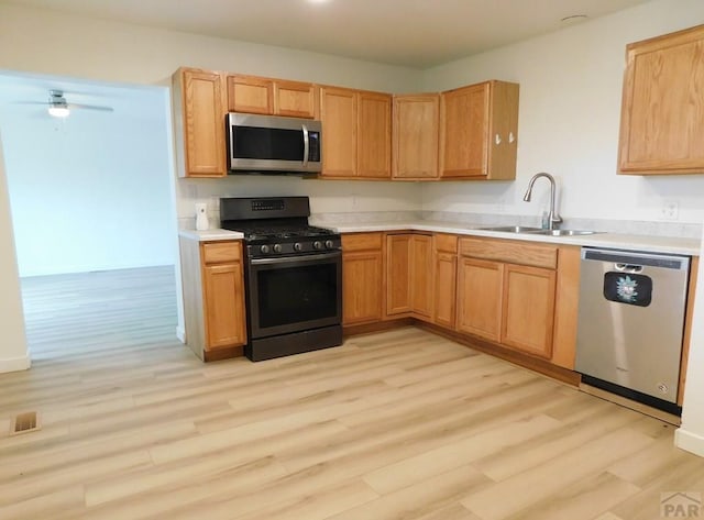 kitchen with light wood finished floors, visible vents, appliances with stainless steel finishes, light countertops, and a sink