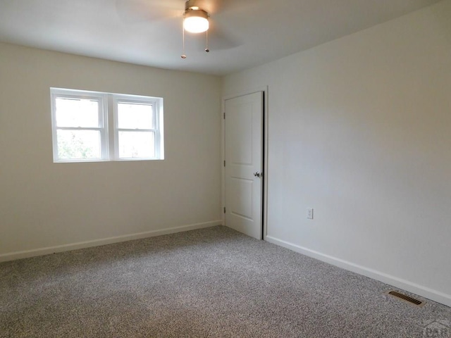 carpeted spare room featuring visible vents, ceiling fan, and baseboards