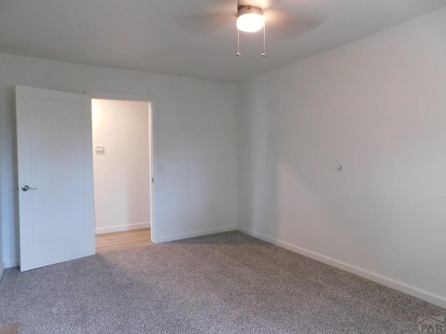 carpeted spare room with ceiling fan and baseboards