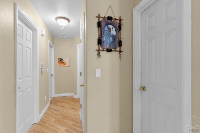 hall featuring light wood finished floors and baseboards