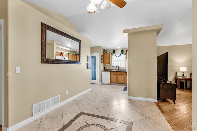 interior space featuring light tile patterned floors, lofted ceiling, visible vents, a ceiling fan, and baseboards