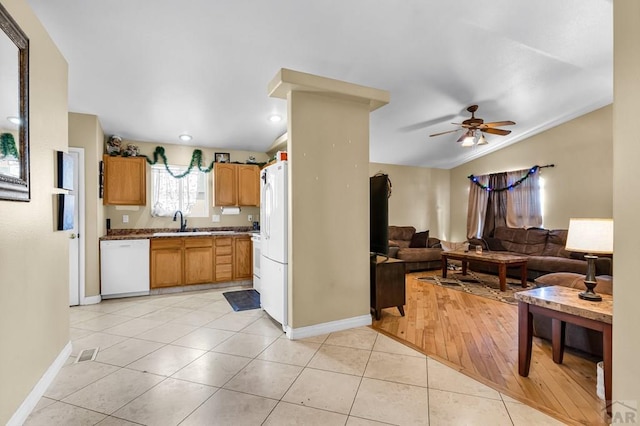 kitchen with light tile patterned floors, open floor plan, vaulted ceiling, a sink, and white appliances