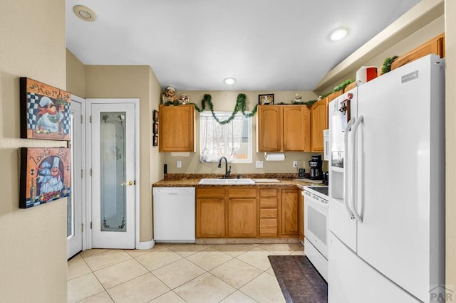 kitchen with light tile patterned floors, white appliances, a sink, light countertops, and brown cabinetry