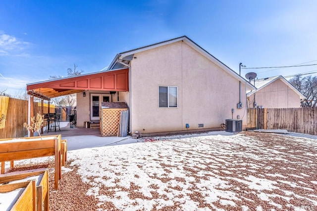 snow covered property featuring crawl space, a fenced backyard, a patio, and stucco siding