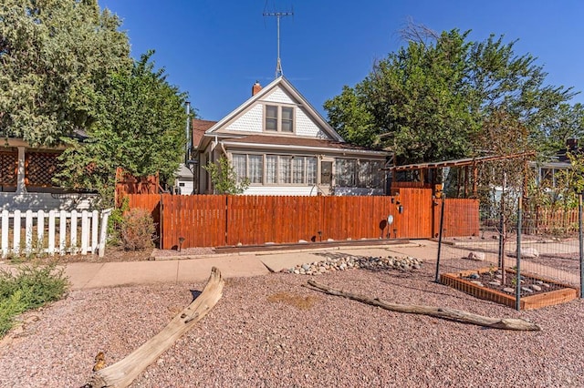 view of front of home featuring a fenced front yard, a chimney, and a gate