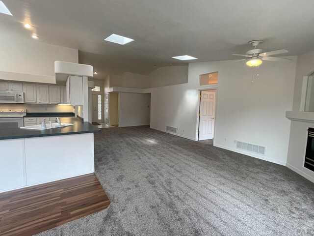 165 Kingsley Ave Unit M, Pueblo, CO 81005 - kitchen featuring white appliances, vaulted ceiling, open floor plan, a sink, and dark countertops