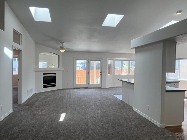 165 Kingsley Ave Unit M, Pueblo, CO 81005 - unfurnished living room featuring a skylight, carpet, baseboards, a fireplace, and a ceiling fan
