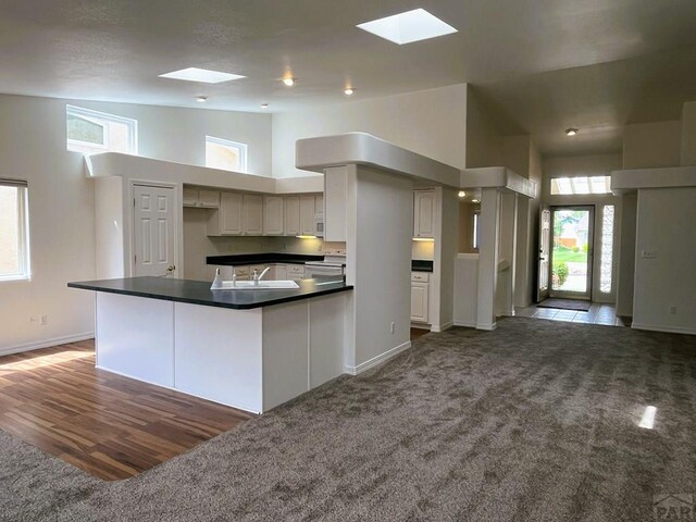 165 Kingsley Ave Unit M, Pueblo, CO 81005 - kitchen featuring carpet flooring, a skylight, high vaulted ceiling, white appliances, and dark countertops