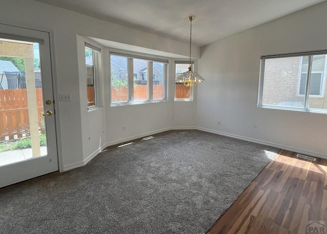 165 Kingsley Ave Unit M, Pueblo, CO 81005 - unfurnished dining area featuring baseboards, a chandelier, and dark wood-style floors